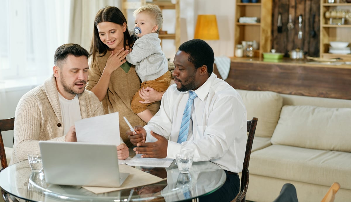 Content family with little boy having visit of African American adviser at home giving consultation on mortgage