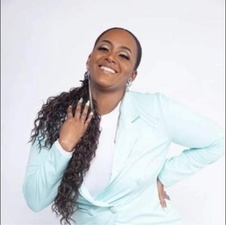 Smiling woman with long dark braided hair wearing a light blue blazer over a white top against a white background